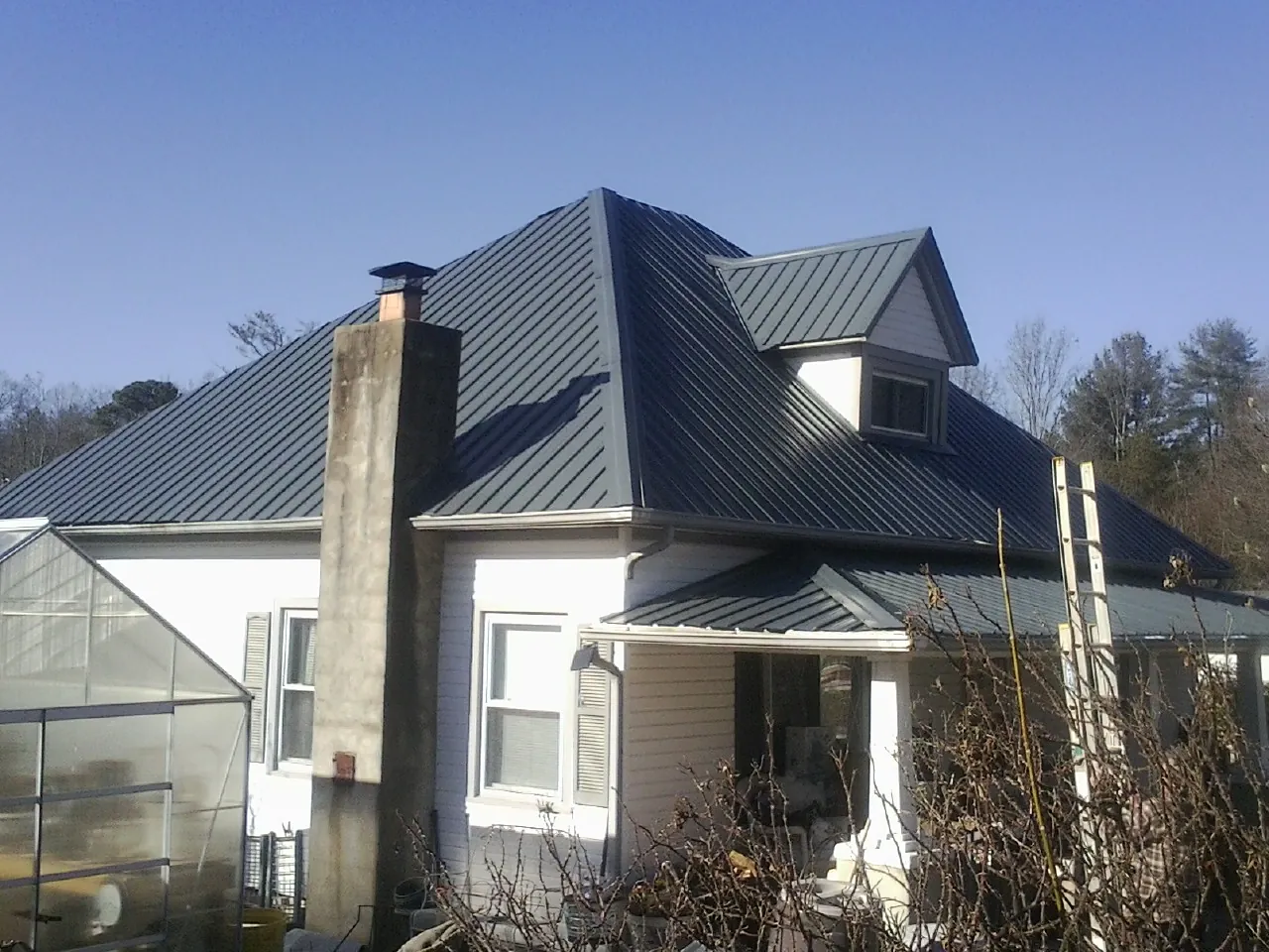 Dark blue standing seam metal roof on a white farmhouse with dormer — Slate & Tile Roof Repair by Roofing Brothers in Atchison