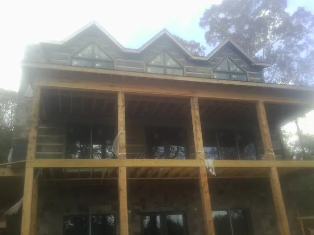 Dormers and porch framing on a large log home under construction — Roof Coating work by our crew in Atchison