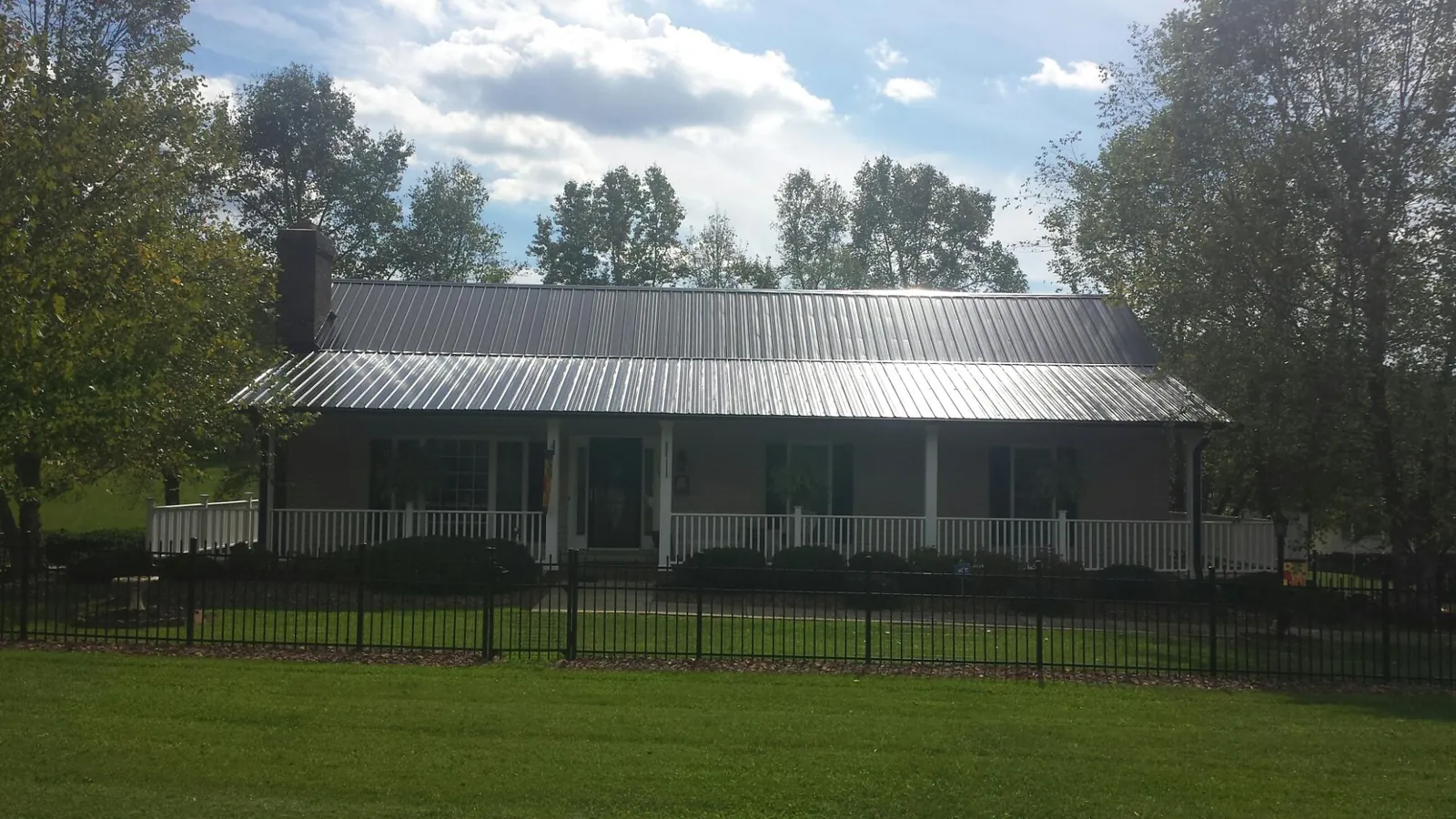 Gray metal roof on a brick ranch with a full width front porch — Gutter Guard Installation work by our crew in Atchison