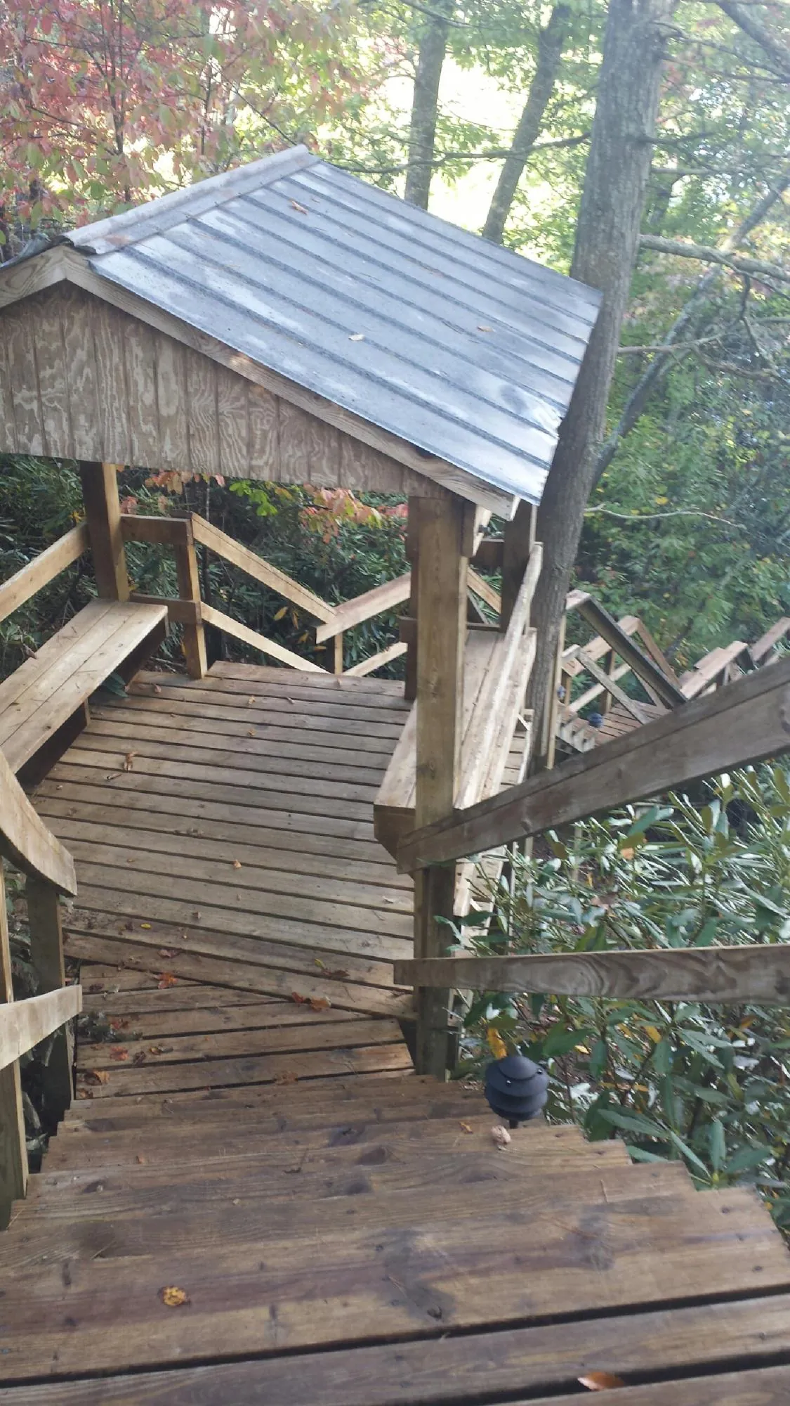 Metal roofed shelter over wooden steps on a wooded walkway — Skylight Repair & Installation work by our crew in Atchison