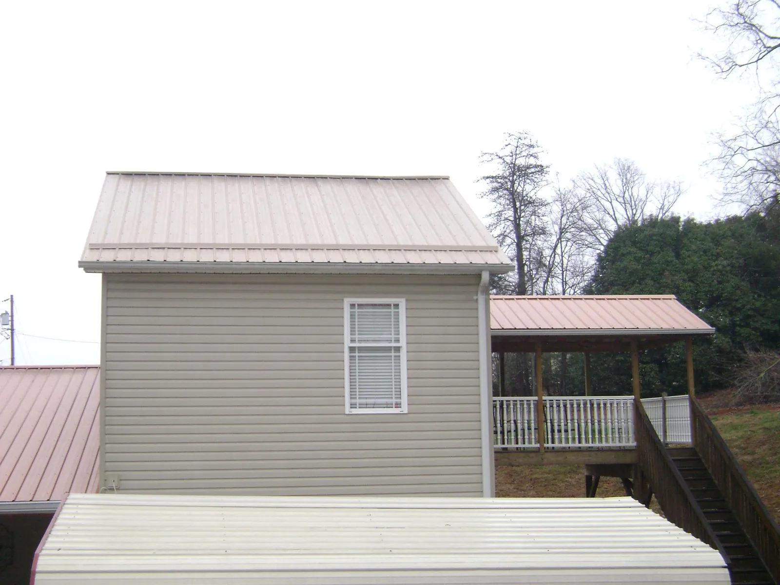 Tan metal roofs on a two story addition and attached porch, from a Roof Replacement job in Atchison